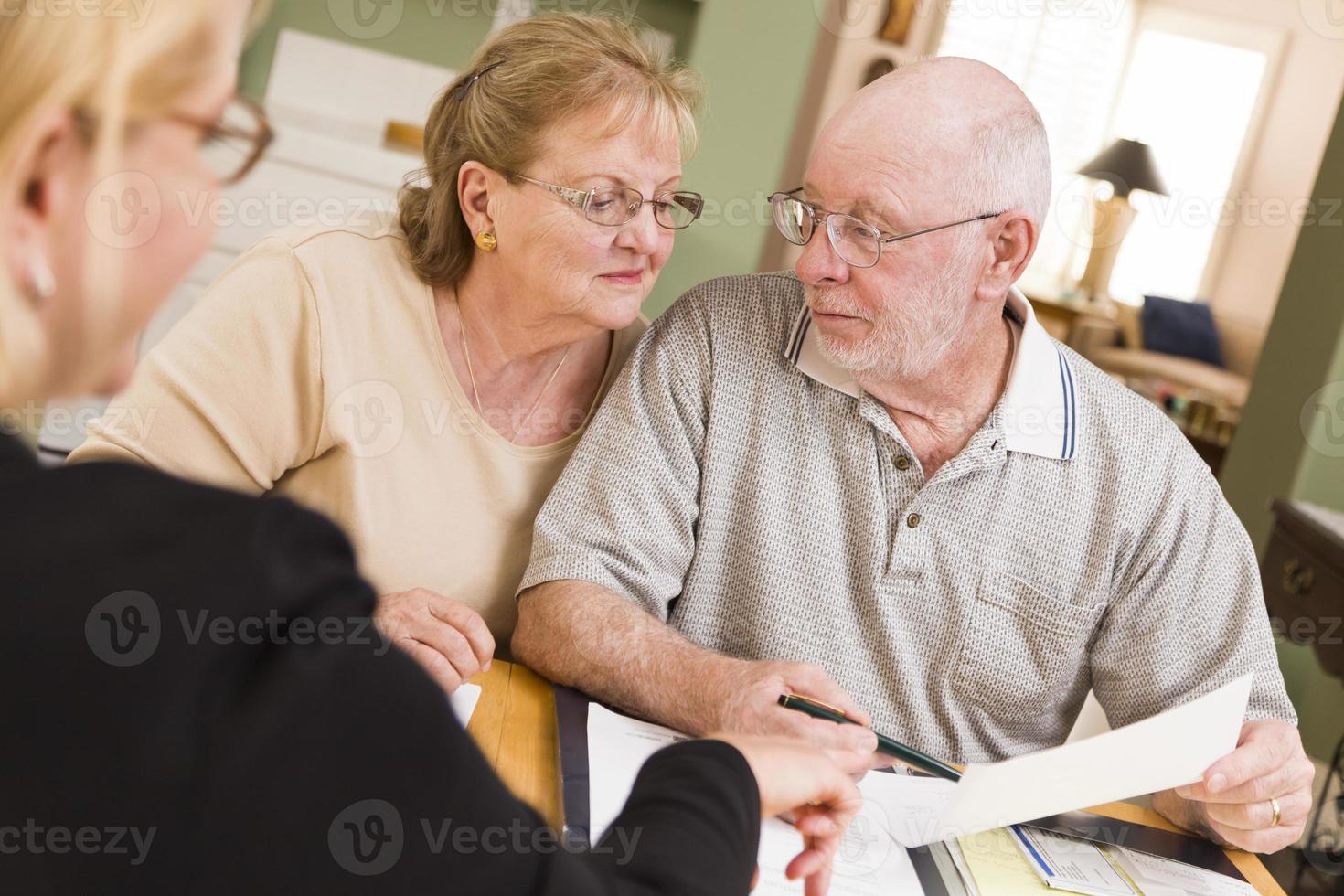 Senior Adult Couple Going Over Papers in Their Home with Agent photo