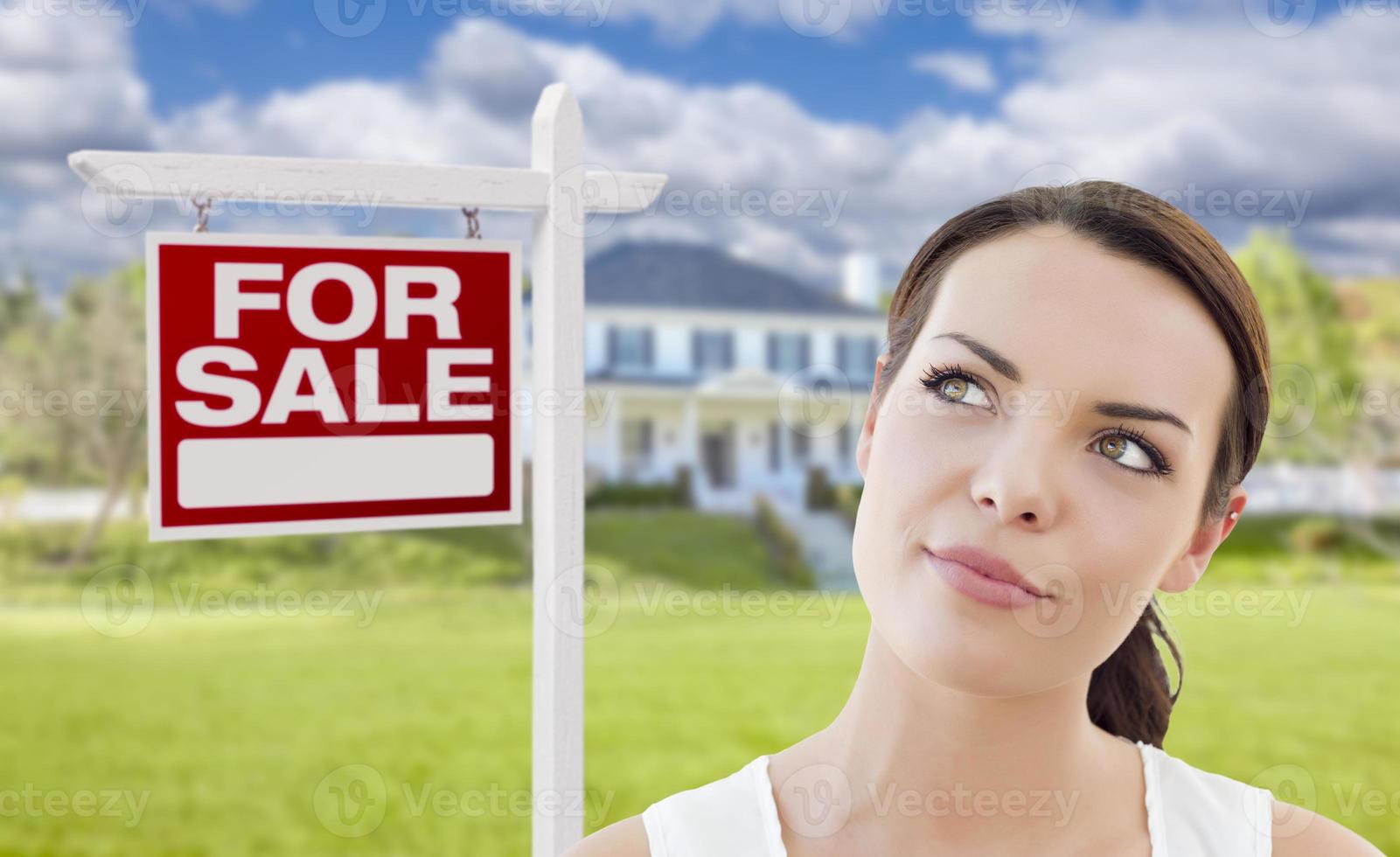 Thinking Woman In Front of House and For Sale Sign photo