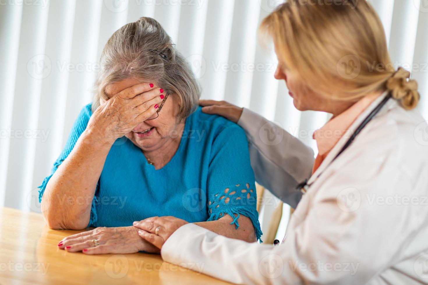 Female Doctor Consoling Distraught Senior Adult Woman photo