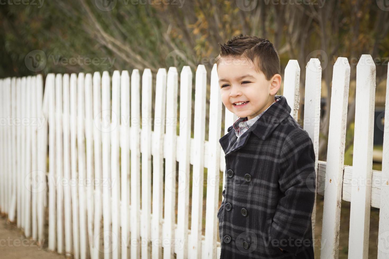 Young Mixed Race Boy Waiting For School Bus Along Fence Outside. photo