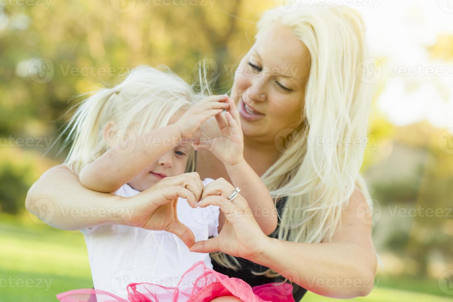 niña con madre haciendo forma de corazón con las manos foto