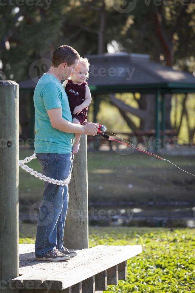 lindo niño y papá pescando en el muelle del lago foto