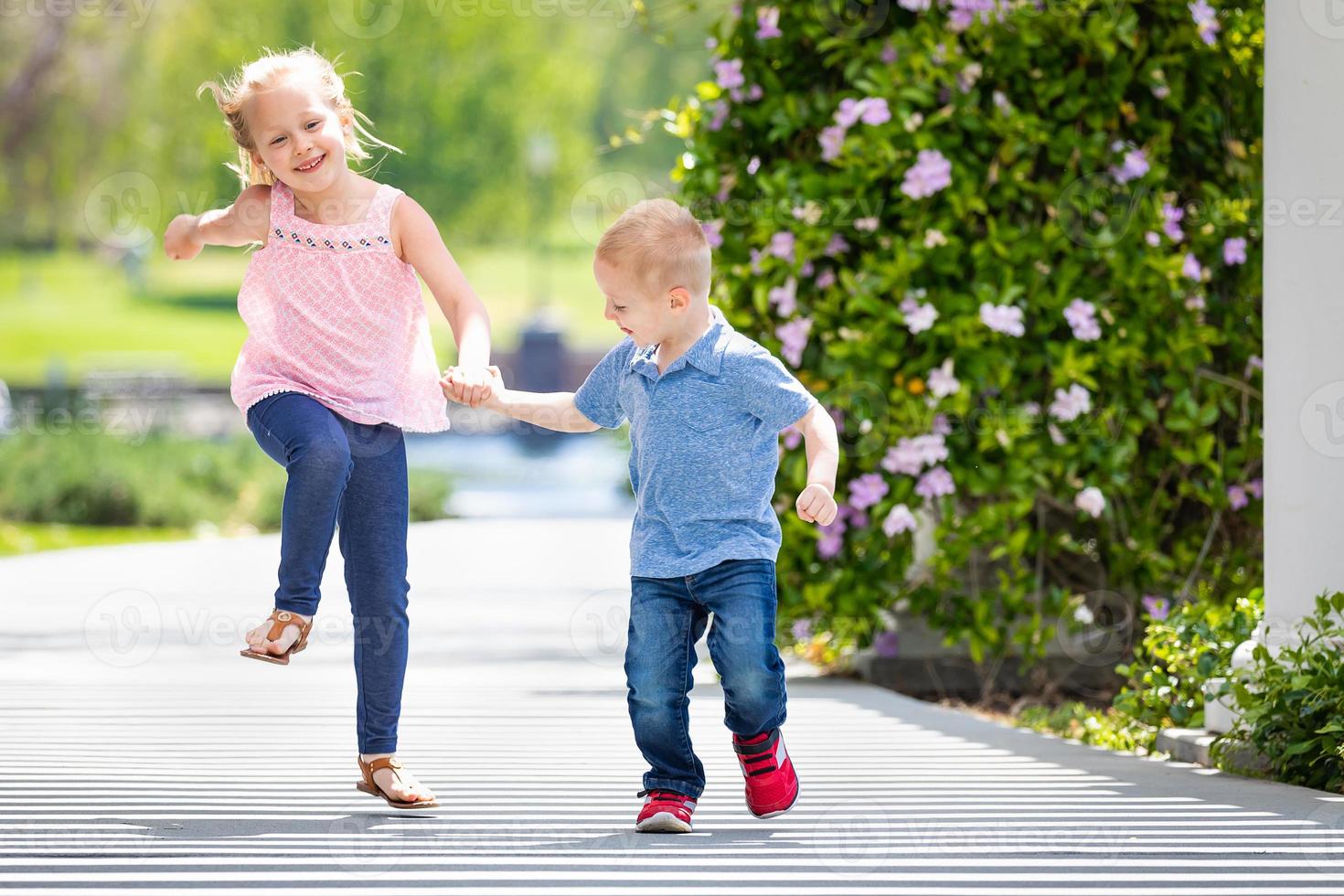 Young Sister and Brother Holding Hands And Running At The Park photo