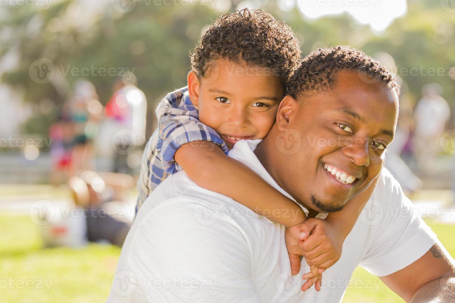 Mixed Race Father and Son Playing Piggyback in Park photo