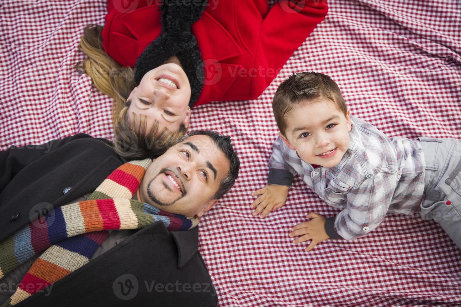 Family in Winter Clothing Laying on Their Backs in Park photo