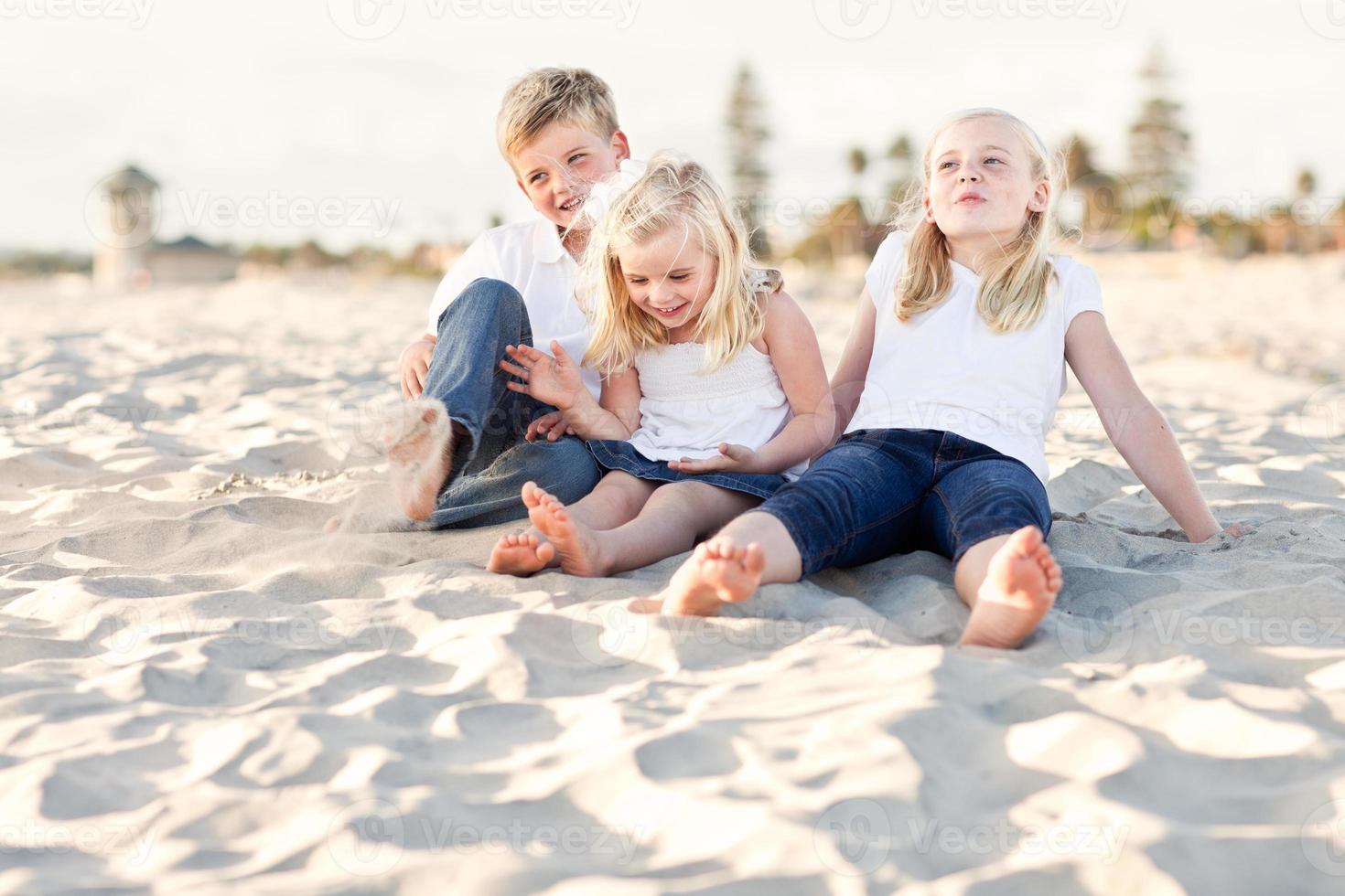 adorables hermanas y hermano divirtiéndose en la playa foto