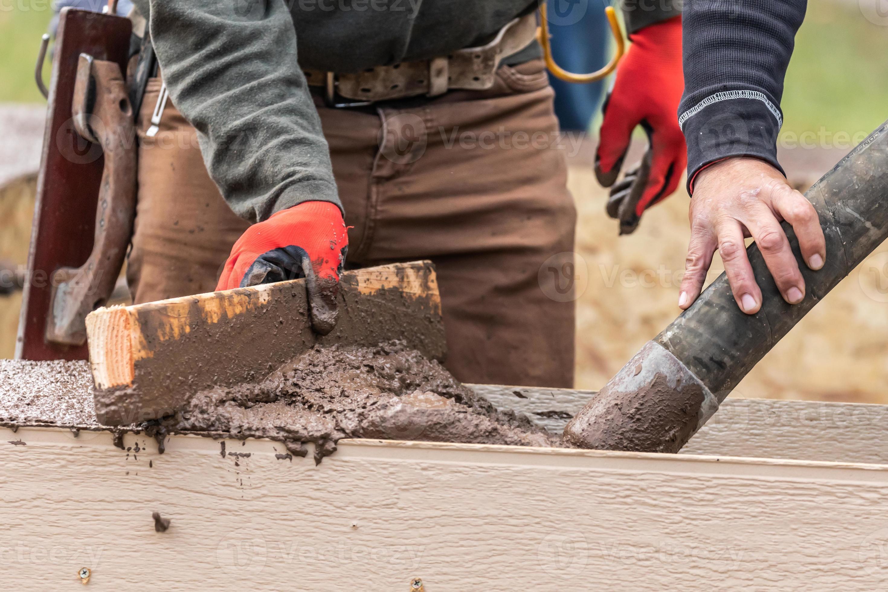 Construction Worker Leveling Wet Cement Into Wood Framing 16359065