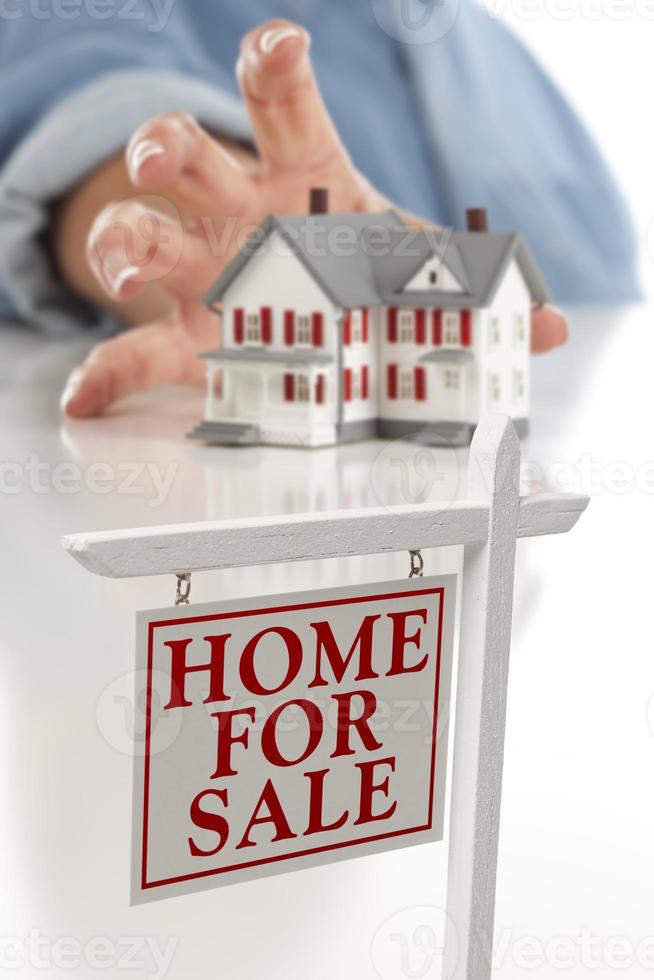 Real Estate Sign in Front of Woman Reaching for House photo