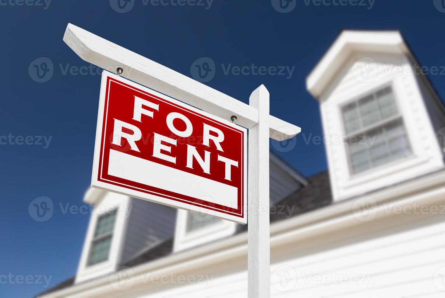 Left Facing For Rent Real Estate Sign In Front of House and Deep Blue Sky. photo