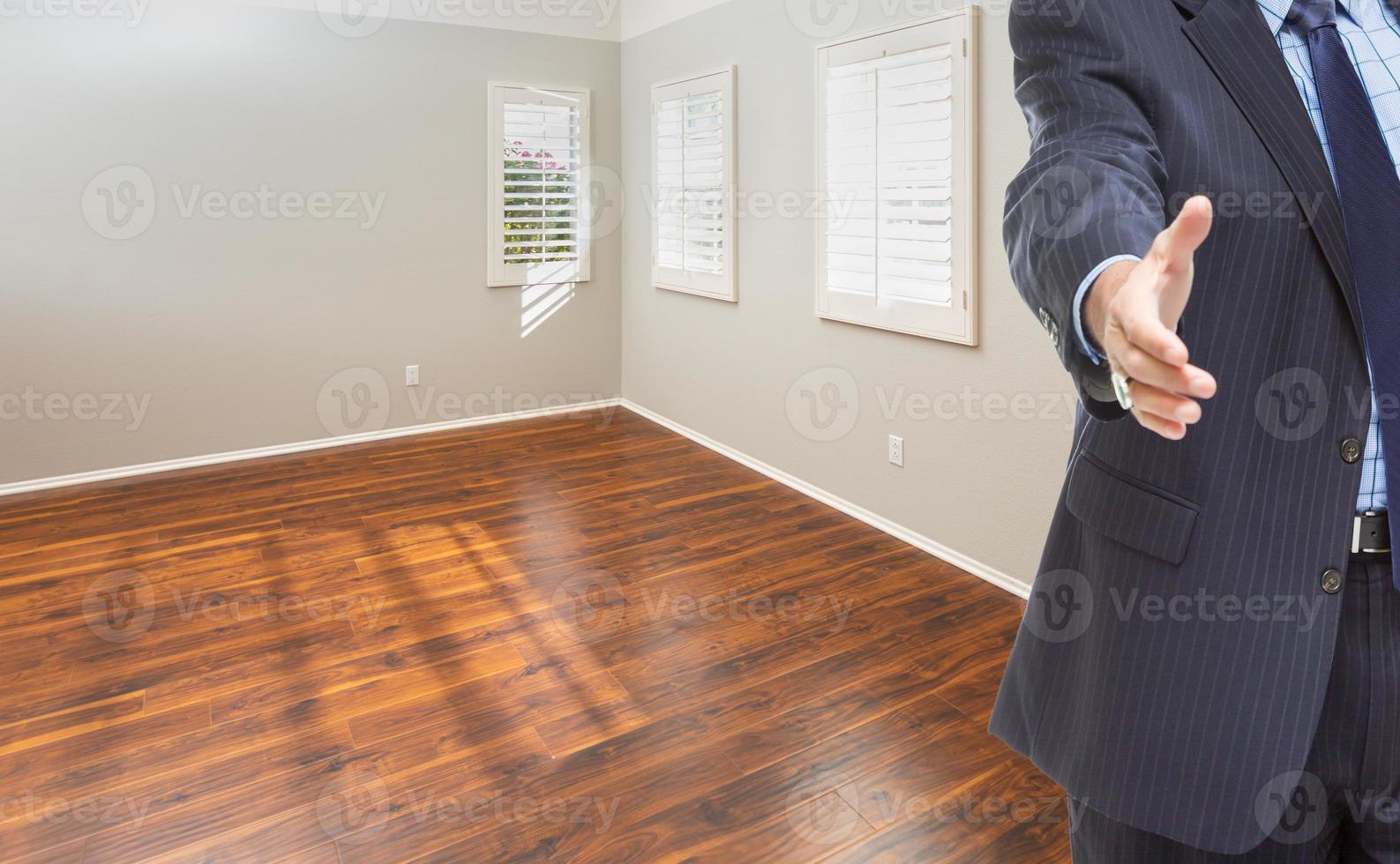 Real Estate Agent Reaches for Handshake Inside Empty Room of New House photo