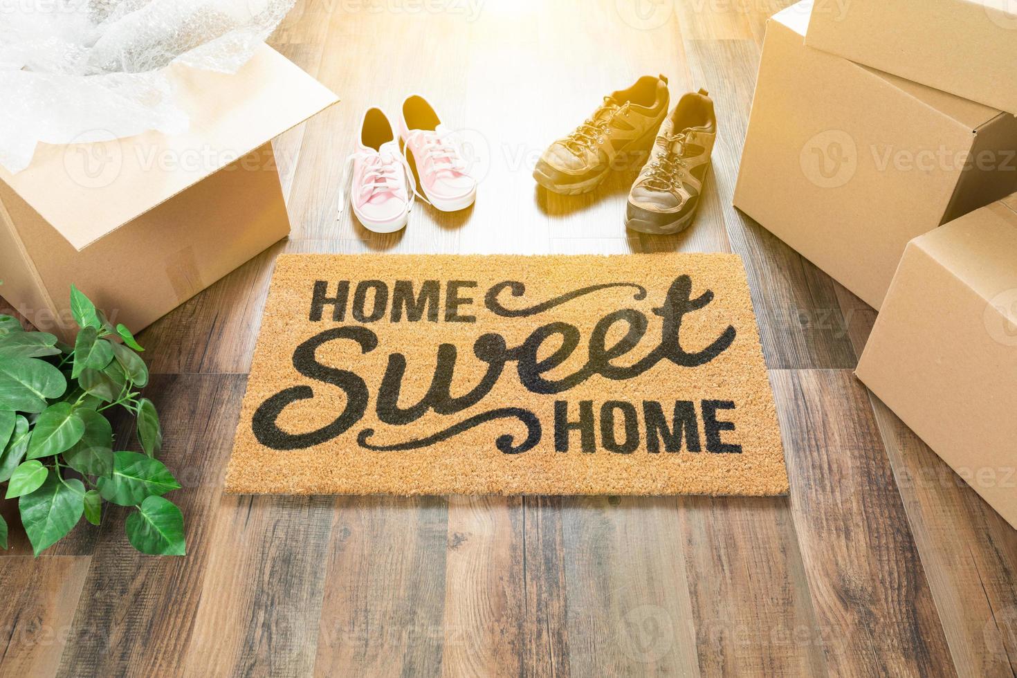 Home Sweet Home Welcome Mat, Moving Boxes, Women and Male Shoes and Plant on Hard Wood Floors. photo