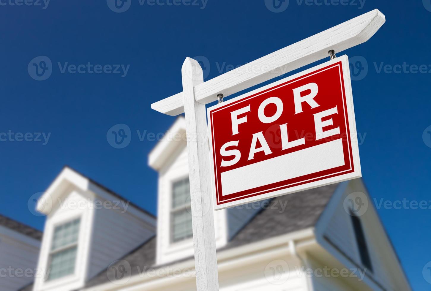 Right Facing For Sale Real Estate Sign In Front of House and Deep Blue Sky. photo