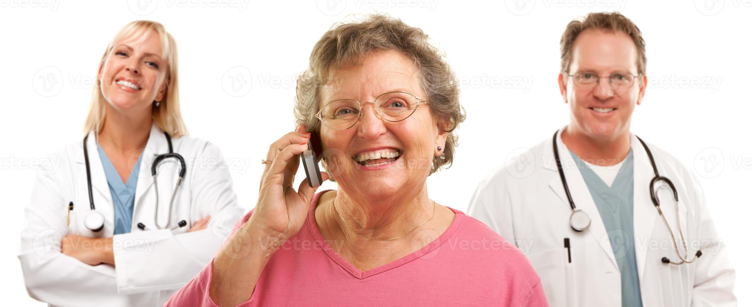 Happy Senior Woman Using Cell Phone and Doctors Behind photo