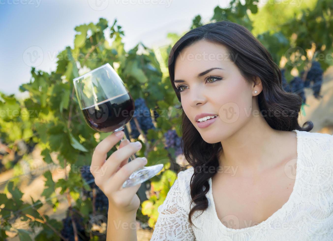 mujer adulta joven disfrutando de una copa de vino en un viñedo foto