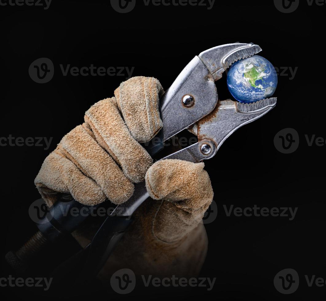 Worker In Construction Gloves Holding Planet Earth with  Vise-grip Wrench photo