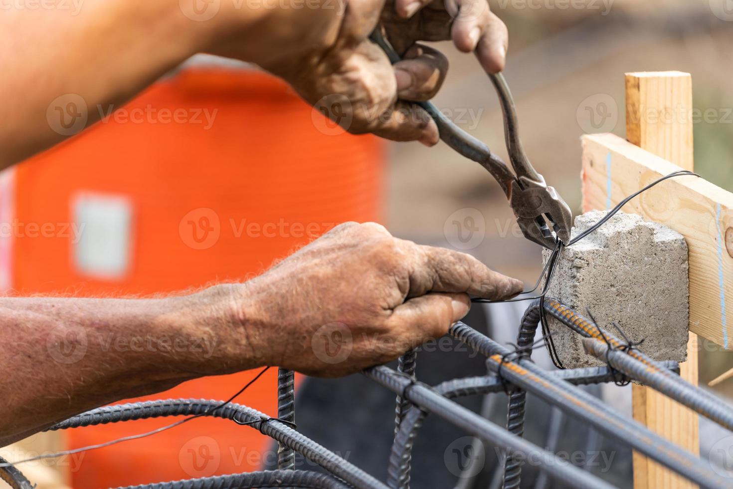 Worker Securing Steel Rebar Framing With Wire Plier Cutter Tool At Construction Site photo