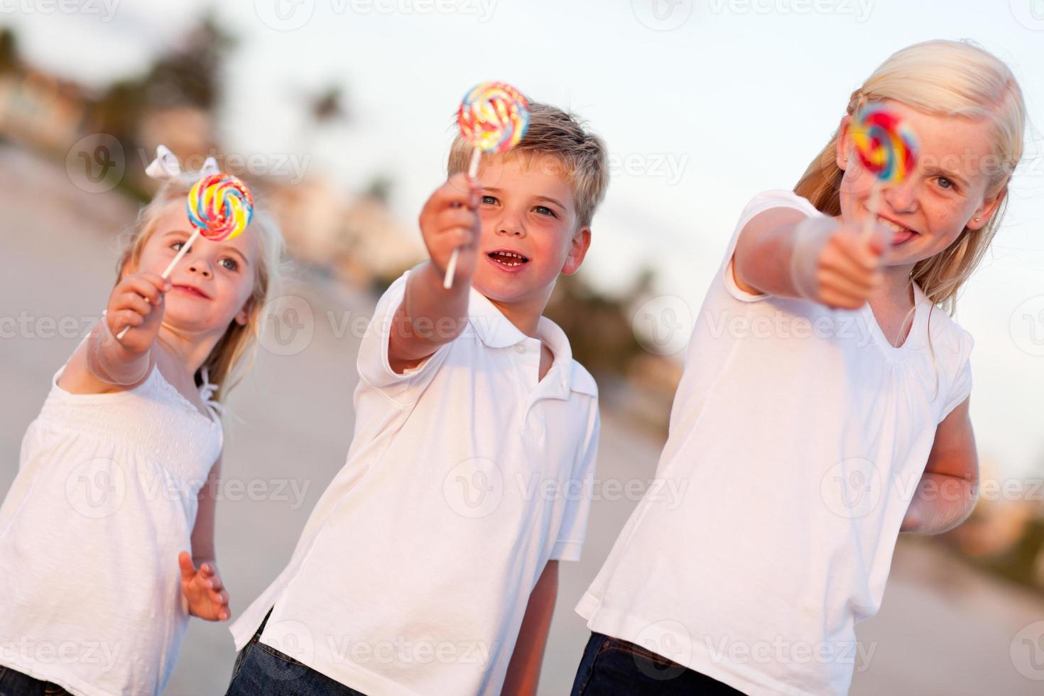 lindo hermano y hermanas disfrutando de sus piruletas afuera foto