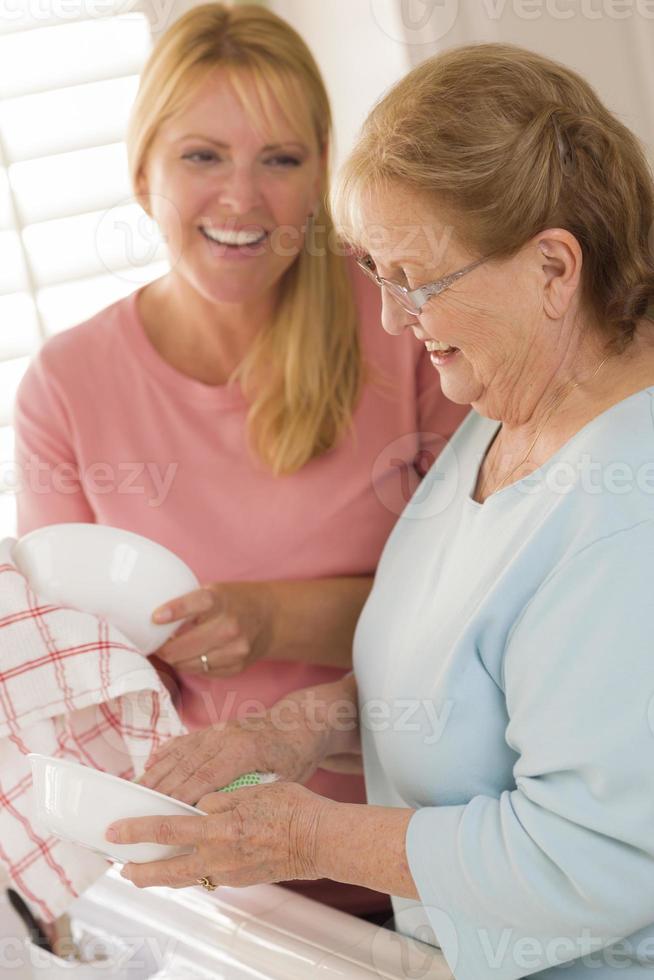 Senior Adult Woman and Young Daughter Talking in Kitchen photo