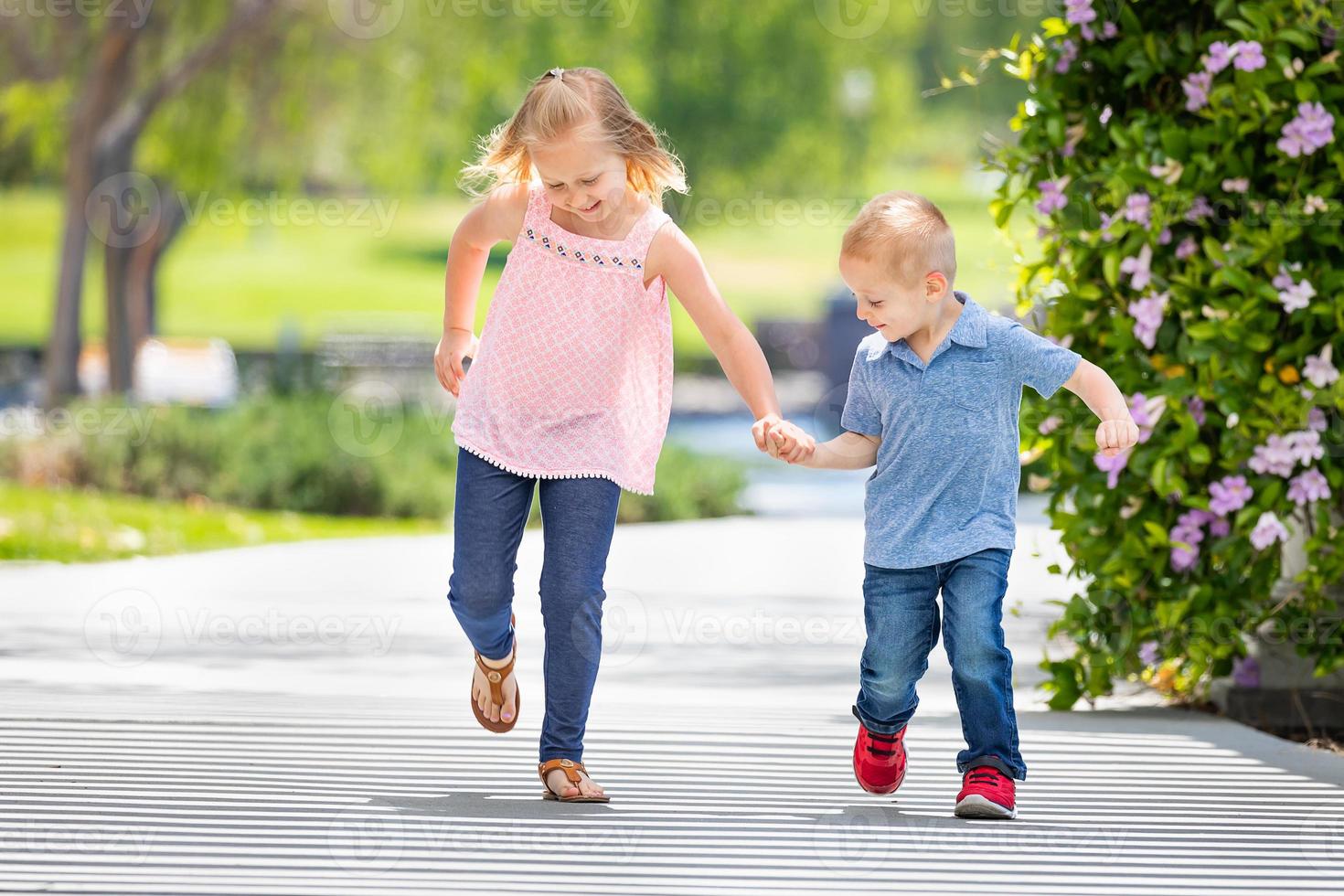 Young Sister and Brother Holding Hands And Running At The Park photo