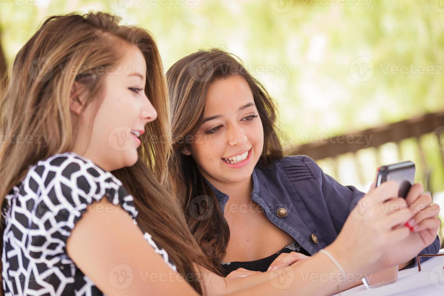 Expressive Young Adult Girlfriends Using Their Smart Cell Phone Outdoors photo