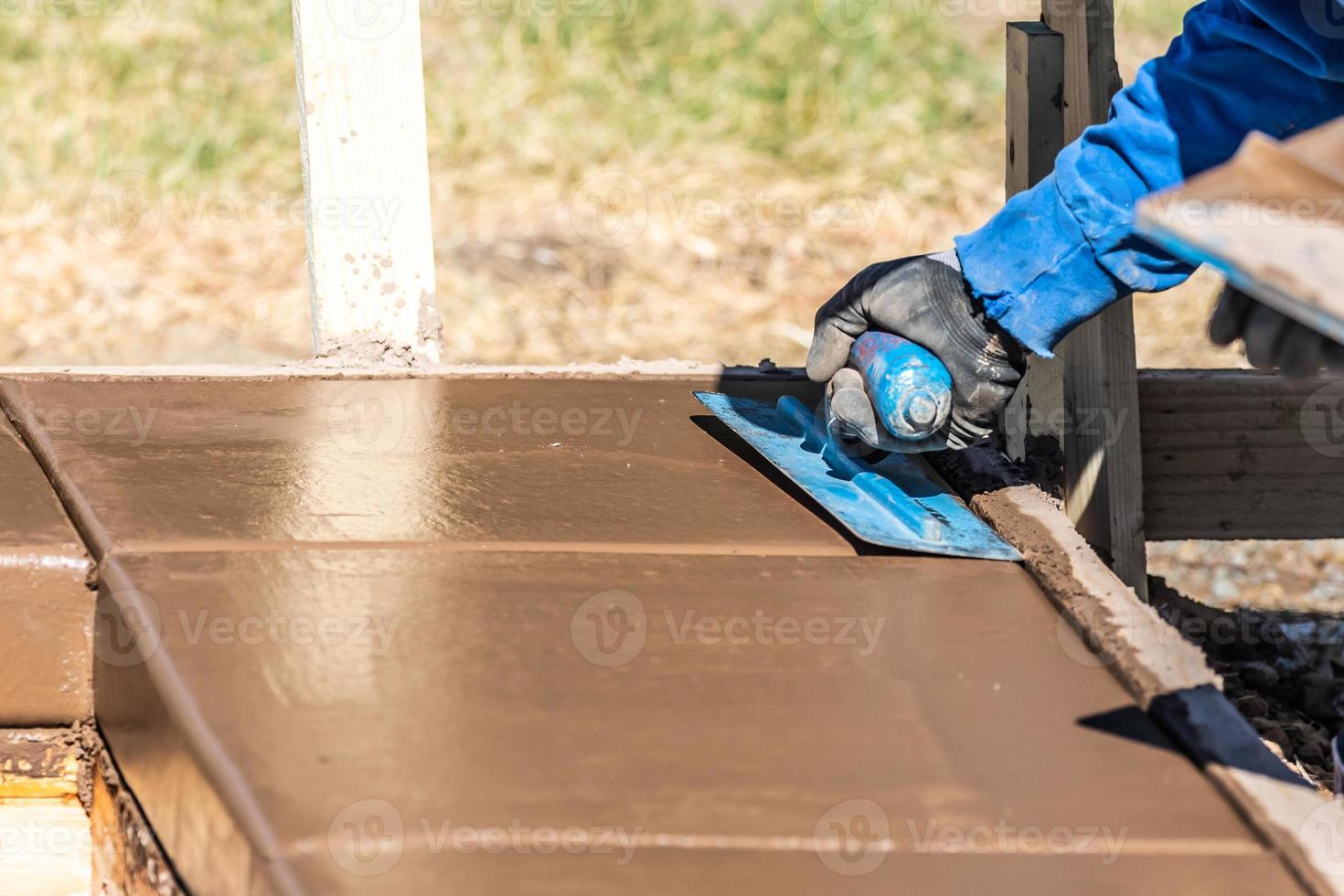 Construction Worker Using Trowel On Wet Cement Forming Coping Around New Pool photo