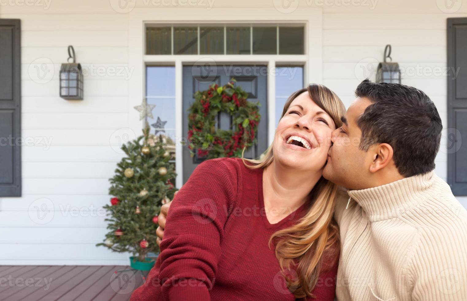 Hispanic and Caucasian Young Adult Couple On Christmas Decorated Front Porch of House photo