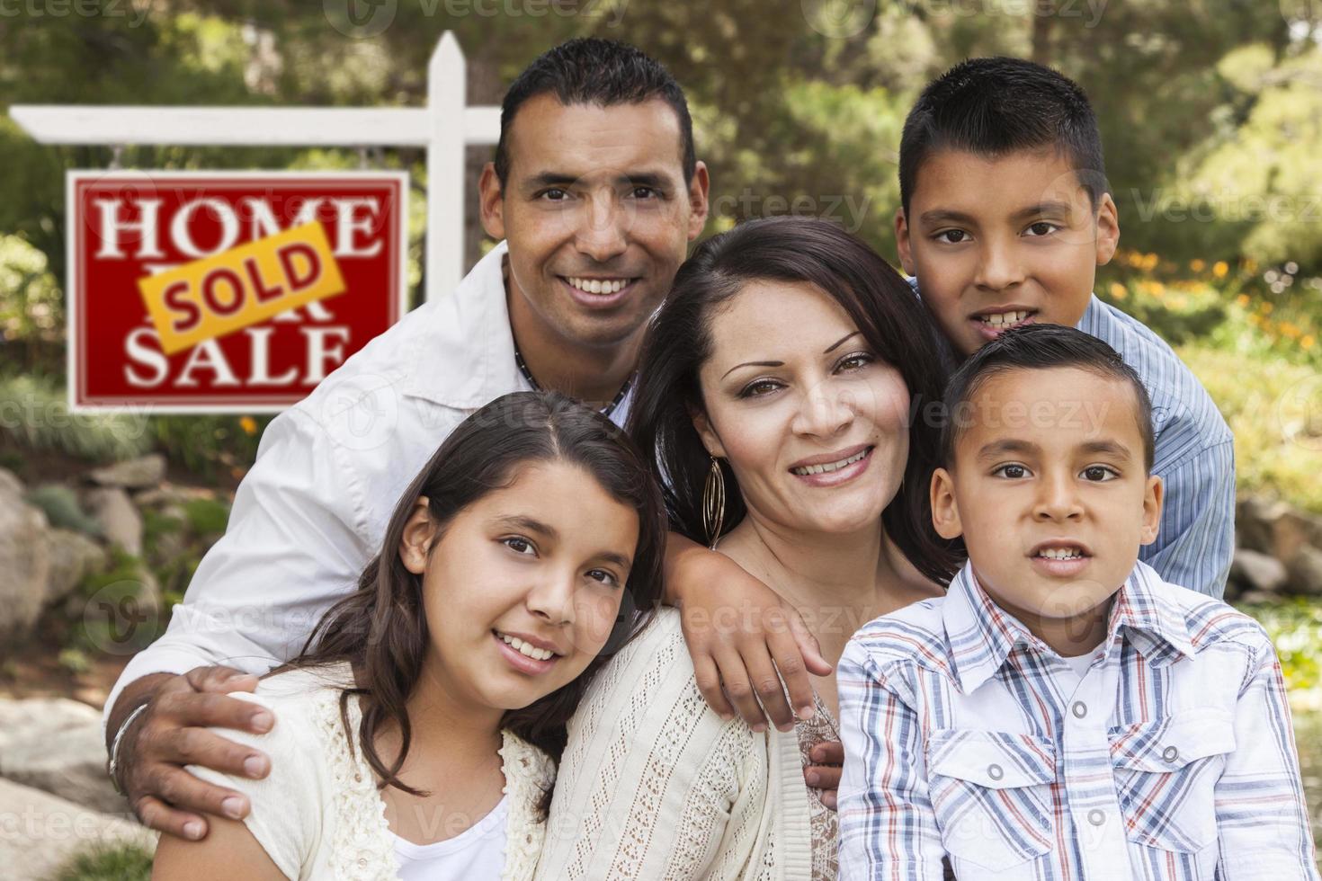 Hispanic Family in Front of Sold Real Estate Sign photo