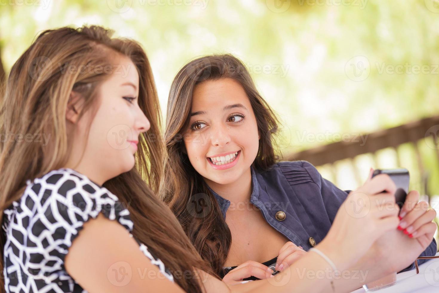 Expressive Young Adult Girlfriends Using Their Smart Cell Phone Outdoors photo