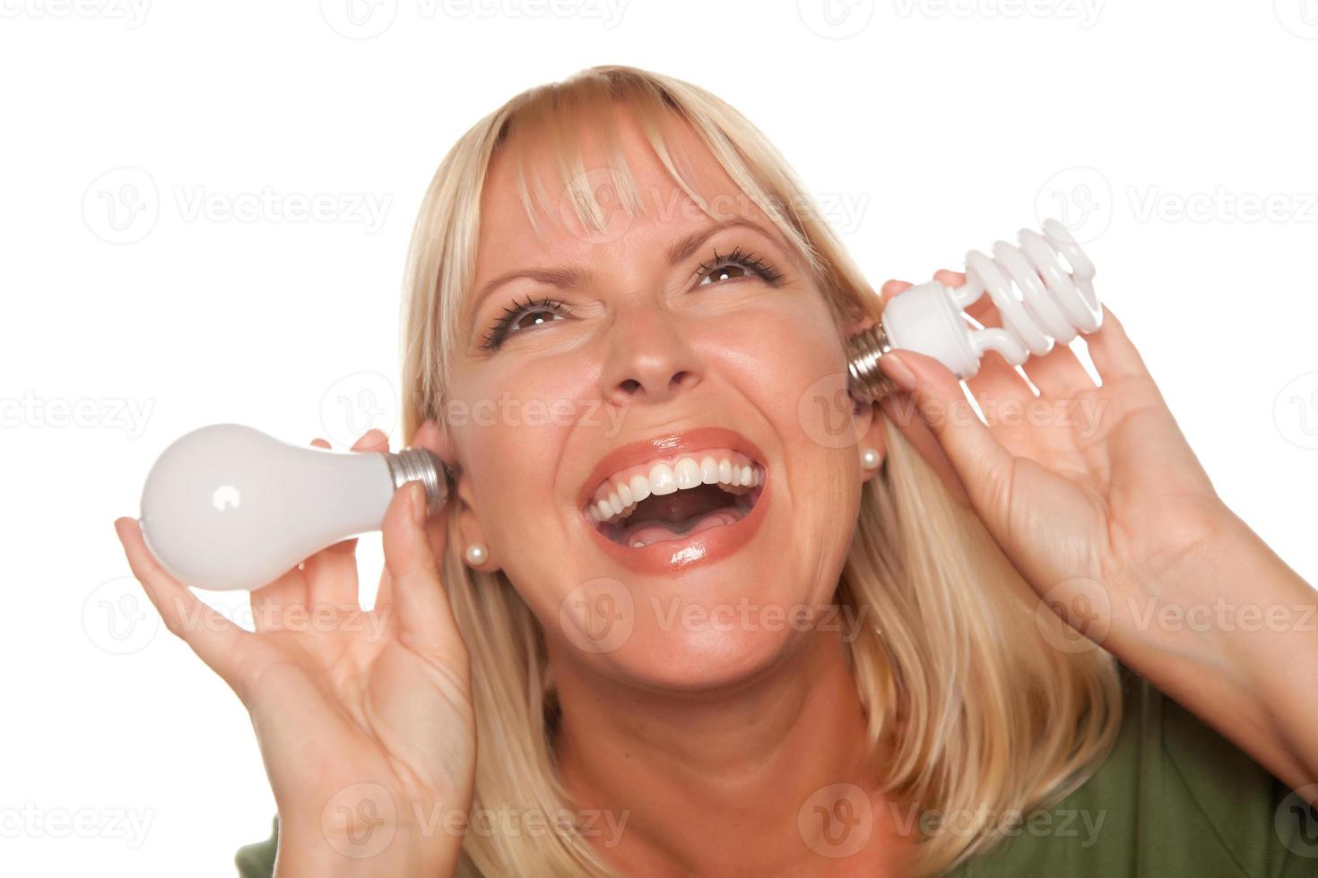 Funny Woman Holding Energy Saving and Regular Light Bulbs to Her Ears photo