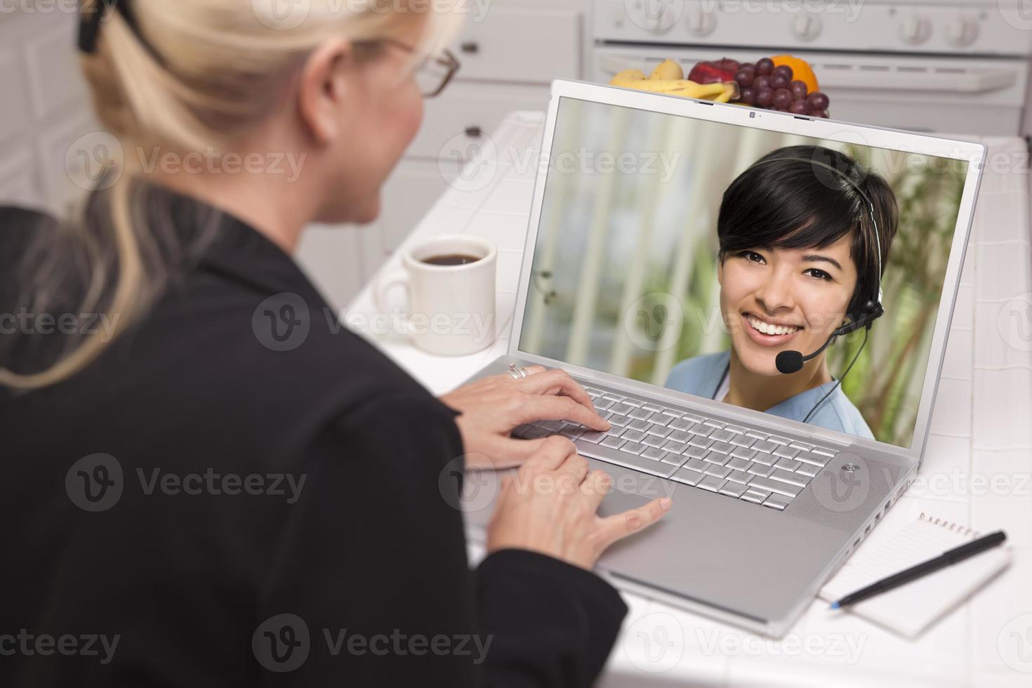 mujer en la cocina usando laptop - en línea con enfermera o médico foto