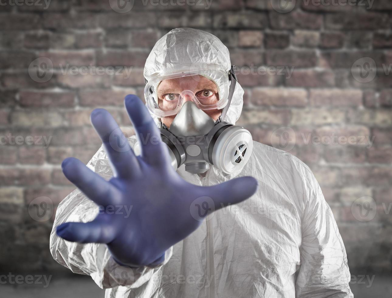 Man Wearing Hazmat Suit, Protective Gas Mask and Goggles Reaching Out With Hand photo