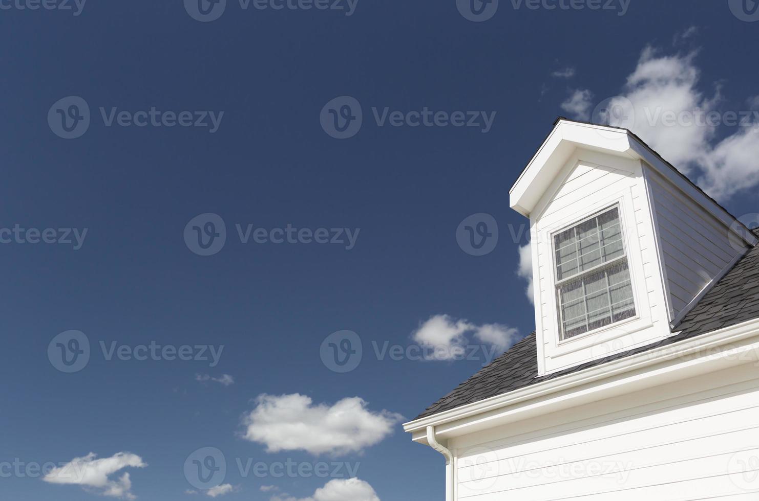 techo de casa y ventanas contra el cielo azul profundo foto