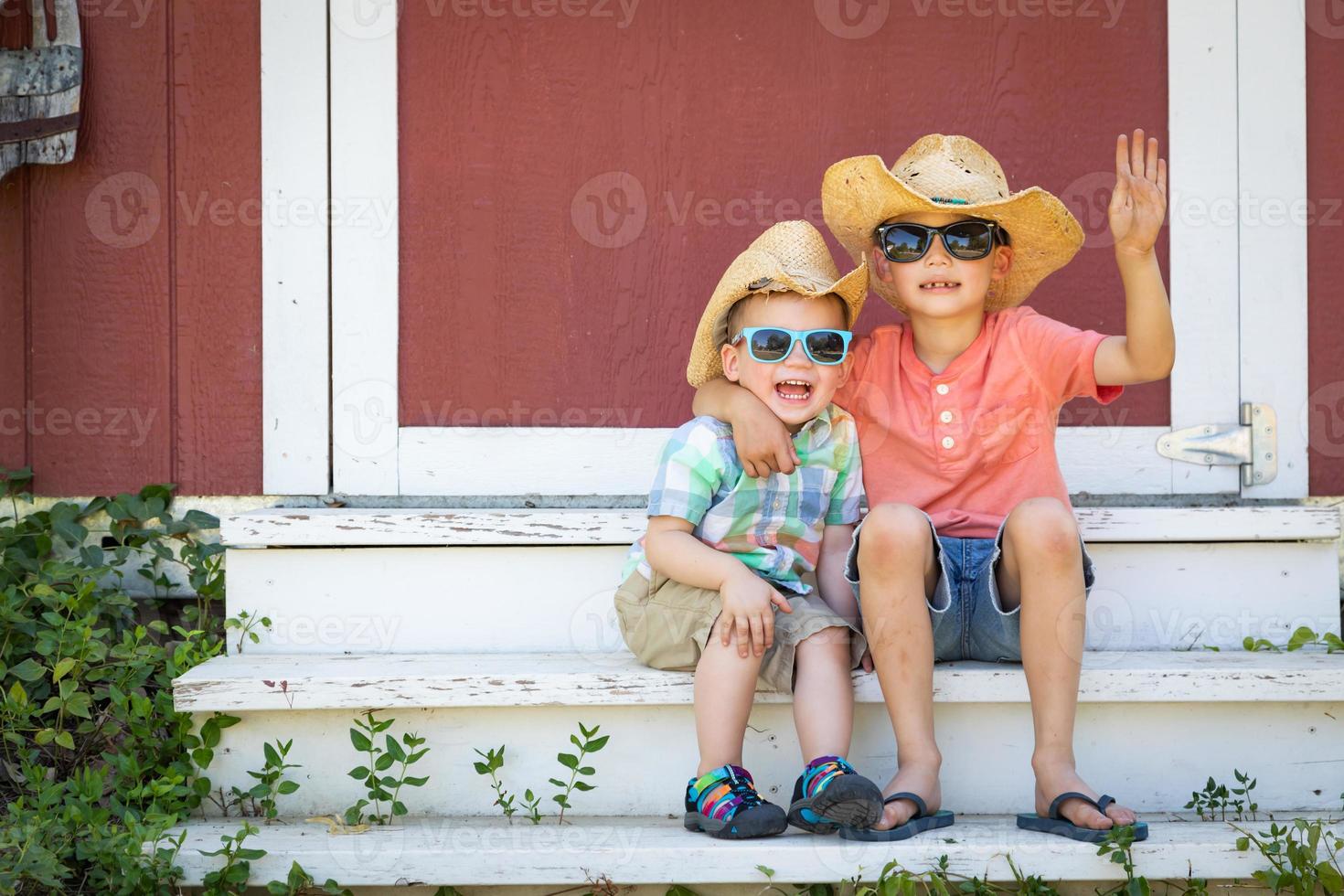 Hermanos jóvenes chinos y caucásicos de raza mixta divirtiéndose con gafas de sol y sombreros de vaquero foto