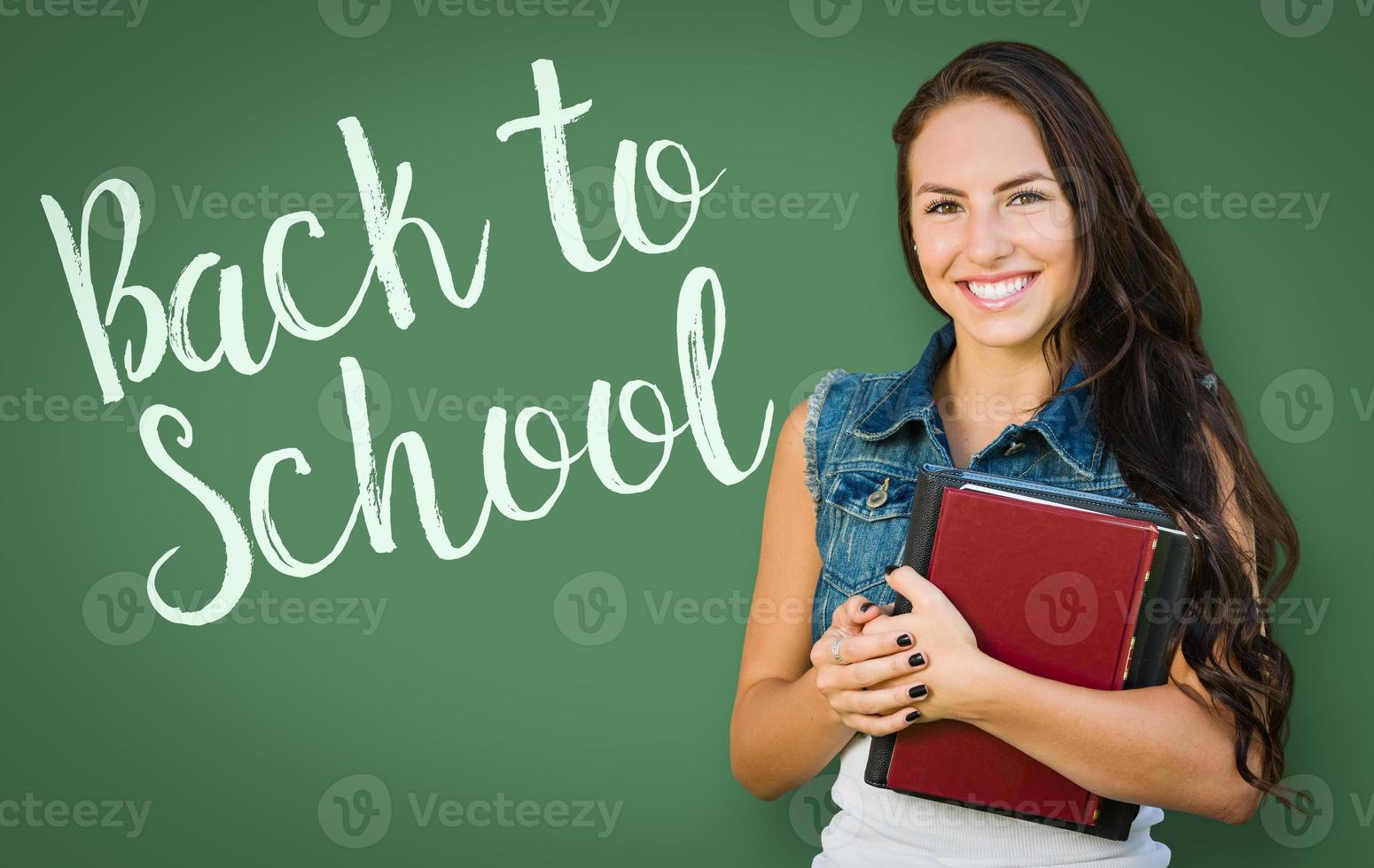 Back To School Written On Chalk Board Behind Mixed Race Young Girl Student Holding Books photo