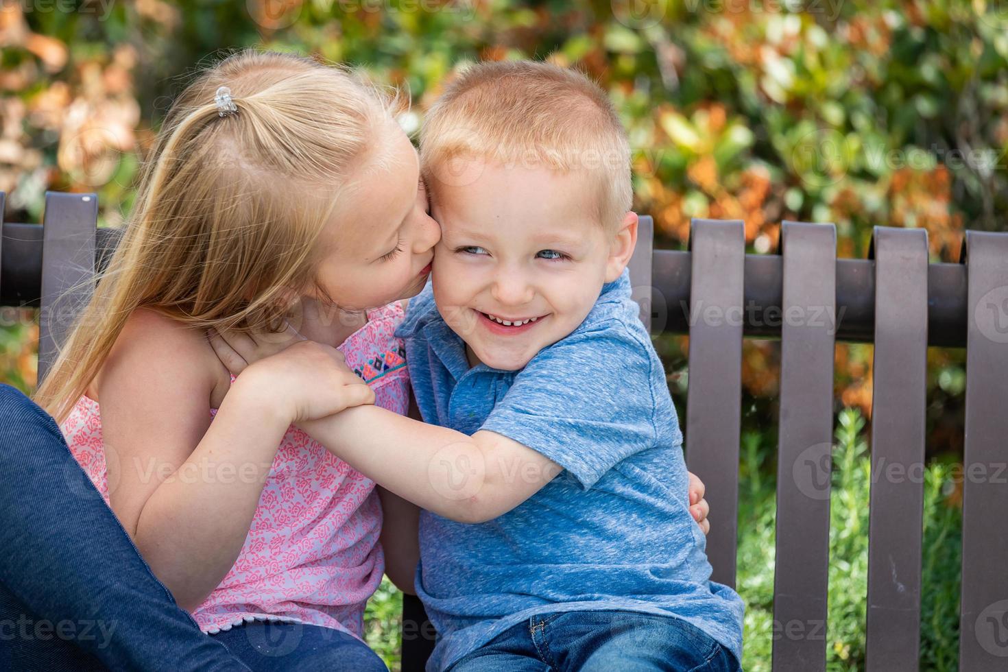 hermana joven y hermano divirtiéndose en el banco en el parque foto