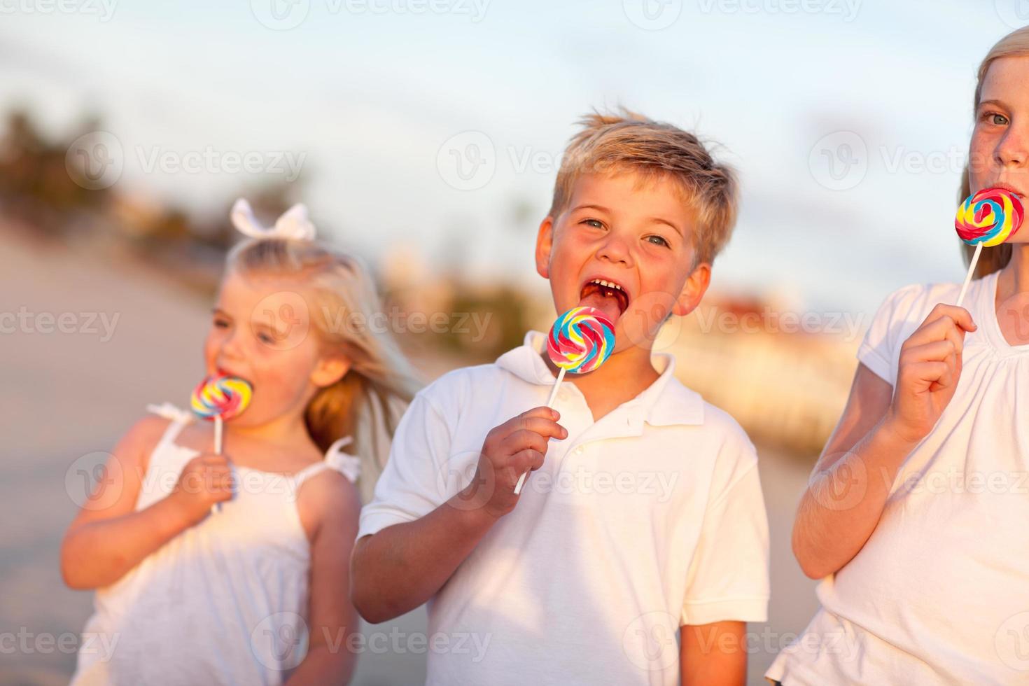 Cute Brother and Sisters Enjoying Their Lollipops Outside photo