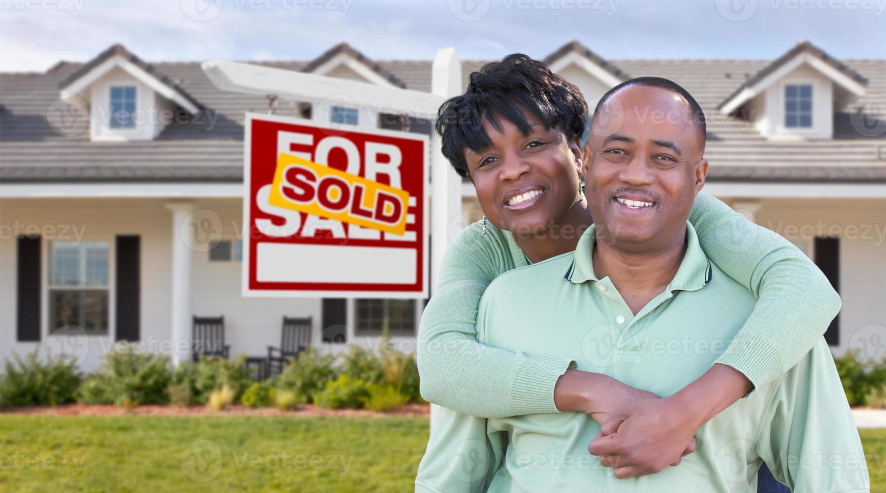 feliz pareja afroamericana frente a una hermosa casa y se vende a la venta cartel de bienes raíces. foto