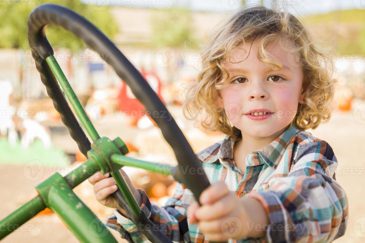 Adorable Young Boy Playing on an Old Tractor Outside photo
