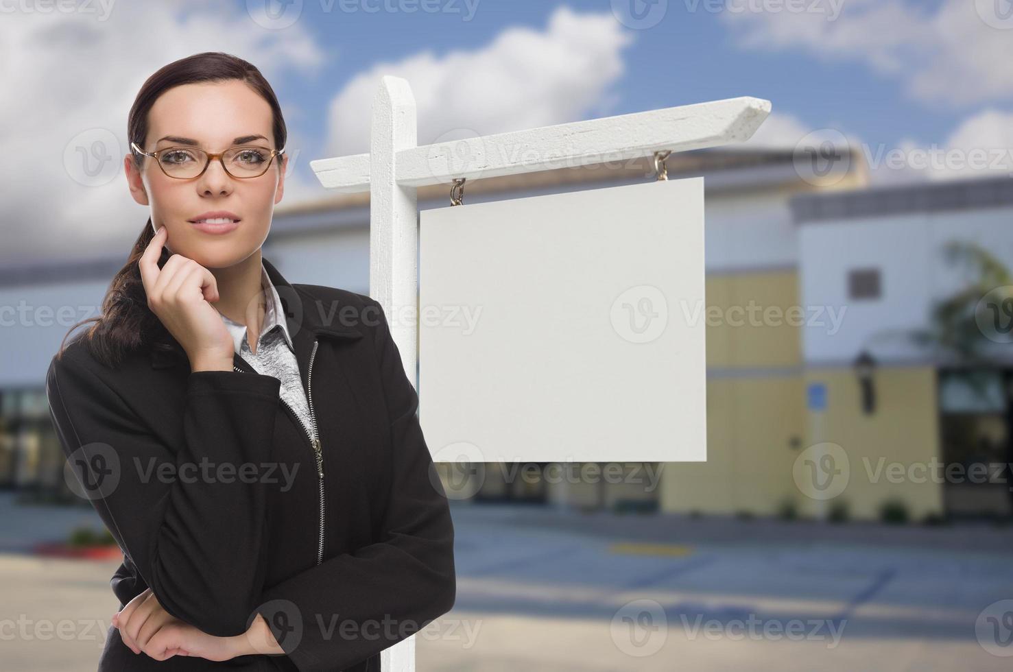 mujer frente a un edificio comercial y un cartel de bienes raíces en blanco foto