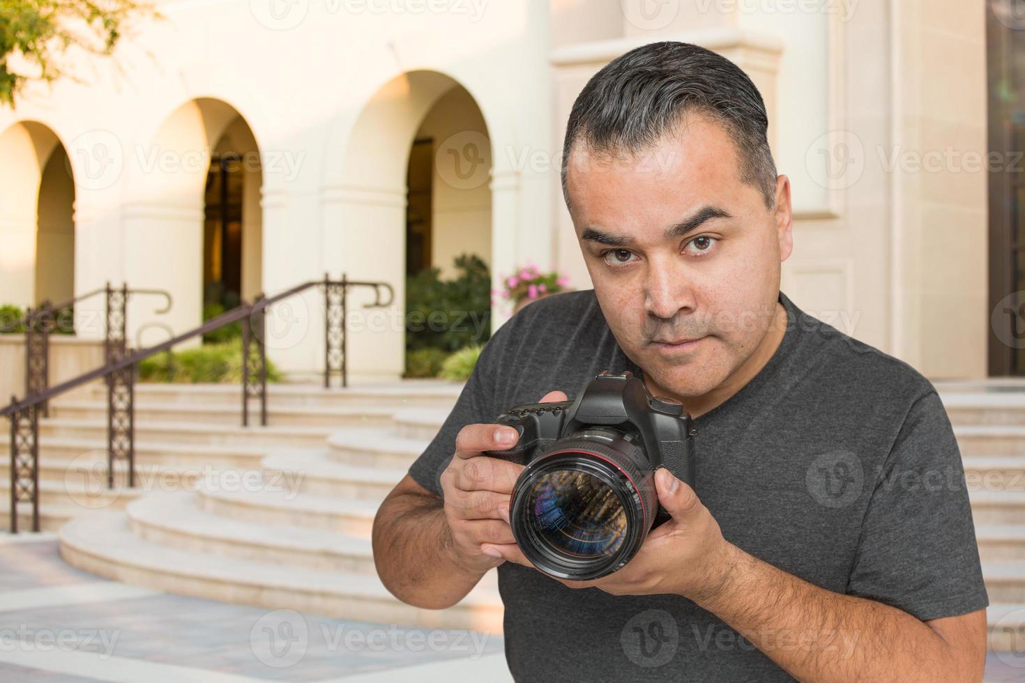 joven fotógrafo hispano con cámara dslr al aire libre foto