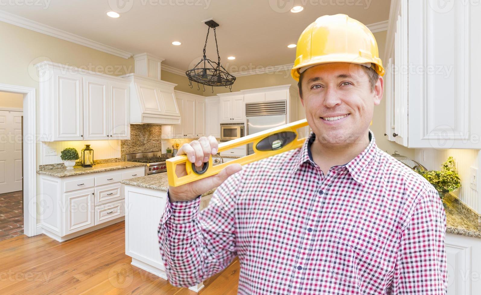 Contractor with Level Wearing Hard Hat Standing In Custom Kitchen photo