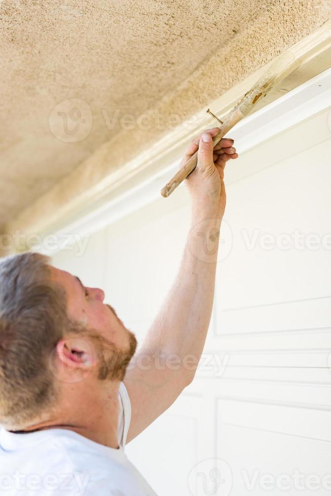 Professional Painter Cutting In With Brush to Paint Garage Door Frame photo