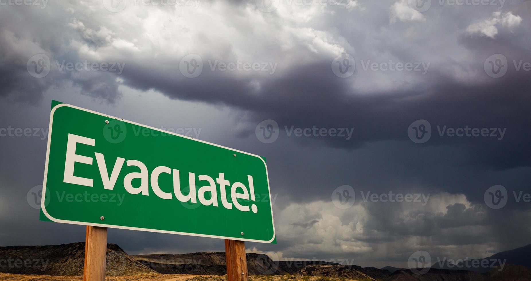 evacuar la señal de carretera verde y las nubes tormentosas foto