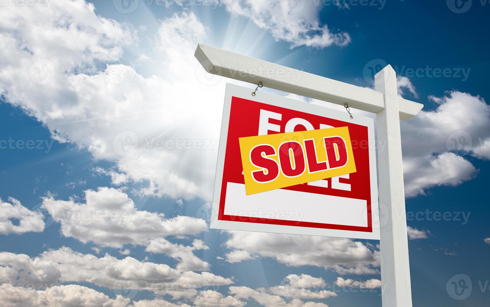 Sold For Sale Real Estate Sign over Clouds and Blue Sky photo