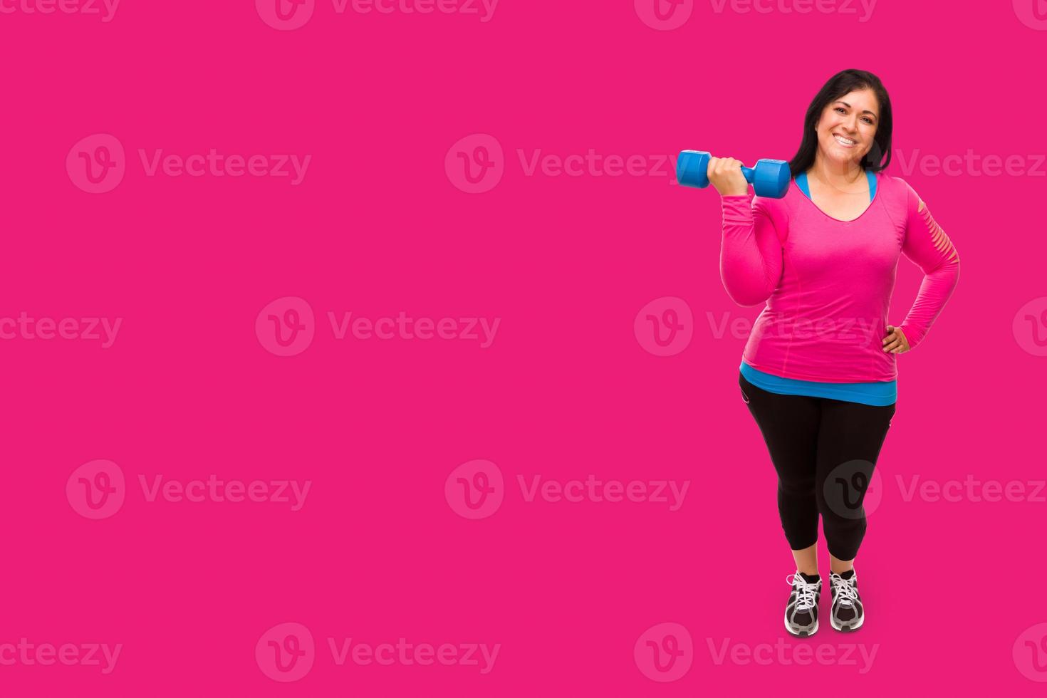 Middle Aged Hispanic Woman In Workout Clothes Holding Dumbbell Against A Bright Magenta Pink Background photo