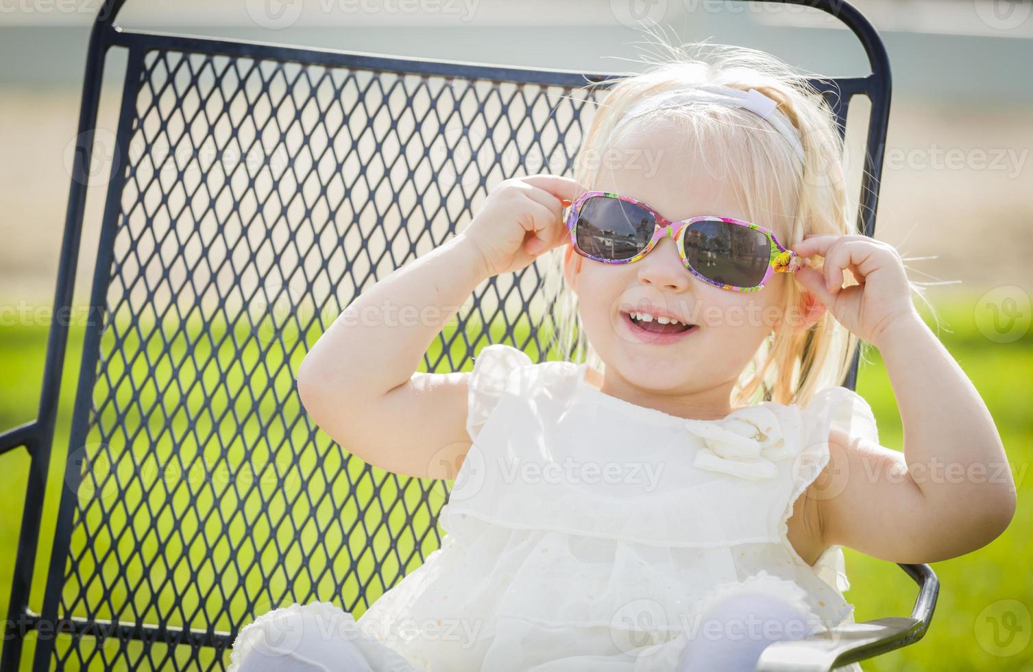 linda niña juguetona con gafas de sol afuera en el parque foto