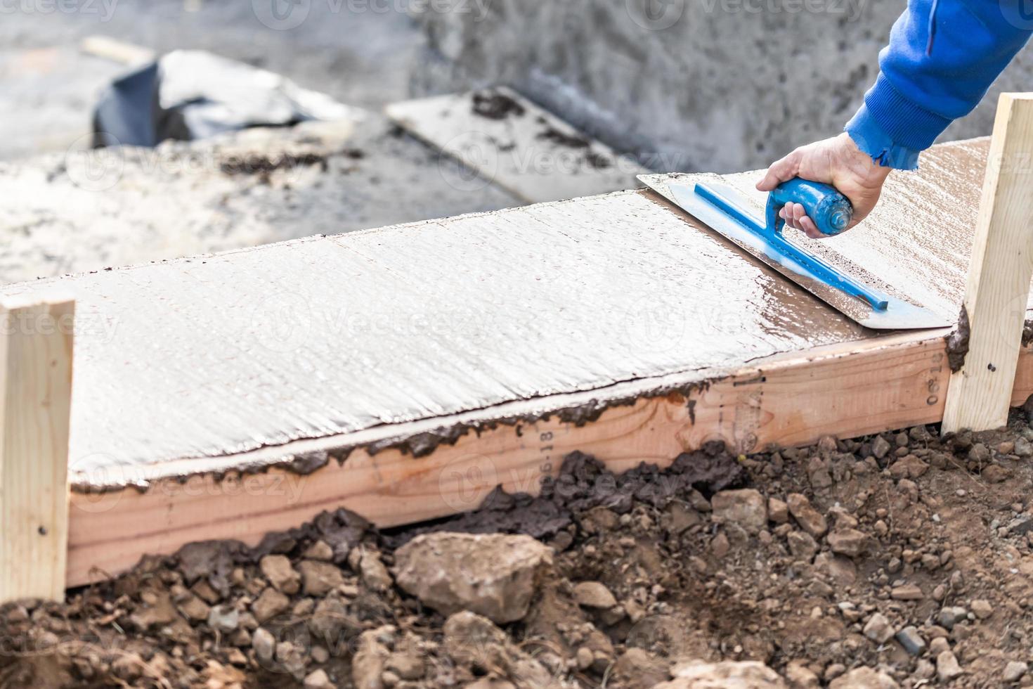 Construction Worker Using Trowel On Wet Cement Forming Coping Around New Pool photo
