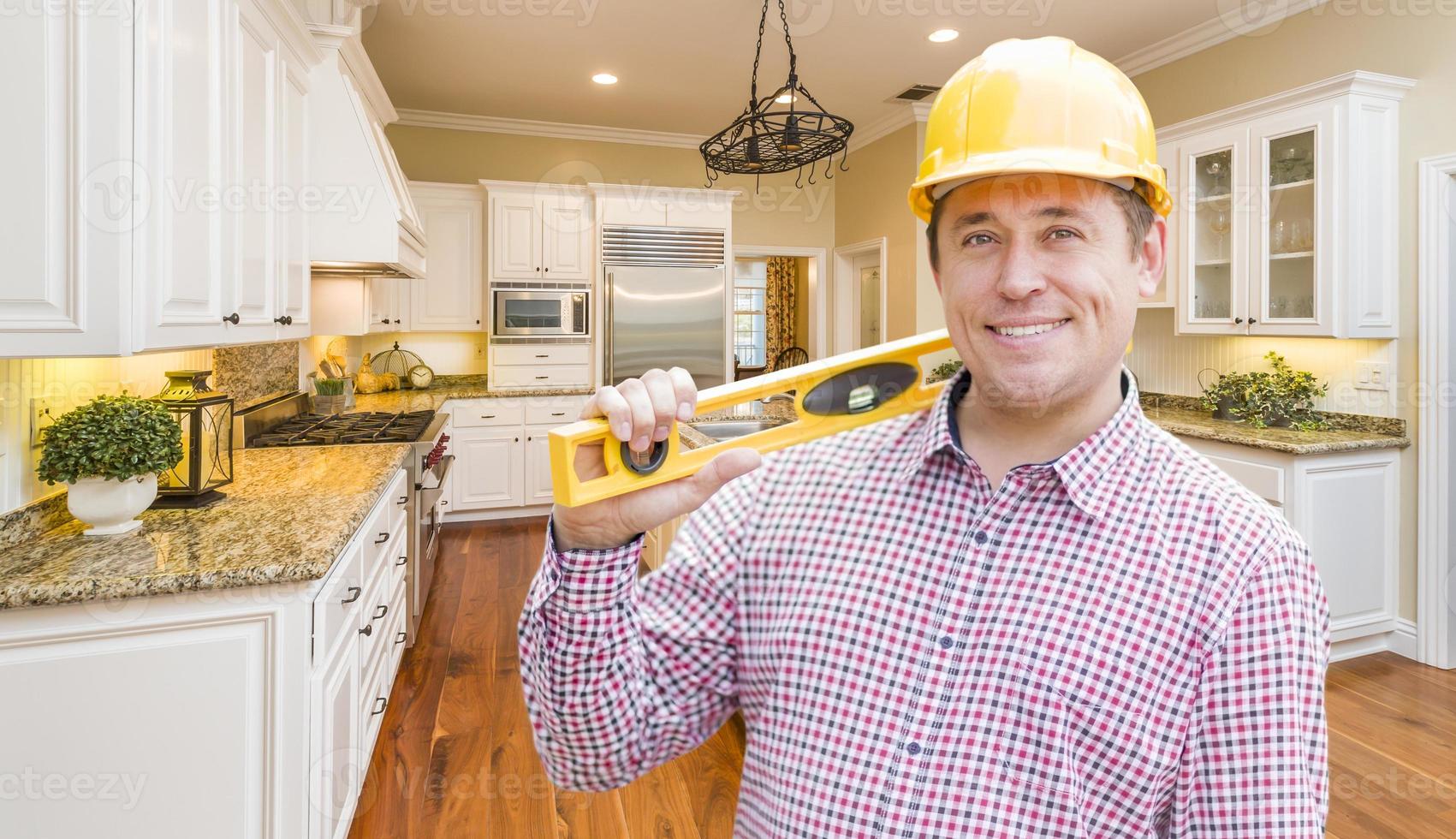 Contractor with Level Wearing Hard Hat Standing In Custom Kitchen photo