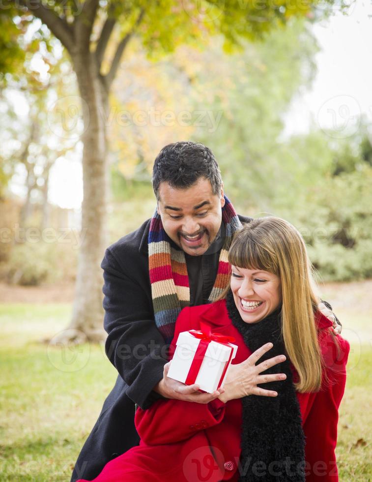 pareja de raza mixta compartiendo regalos de navidad o san valentín afuera foto