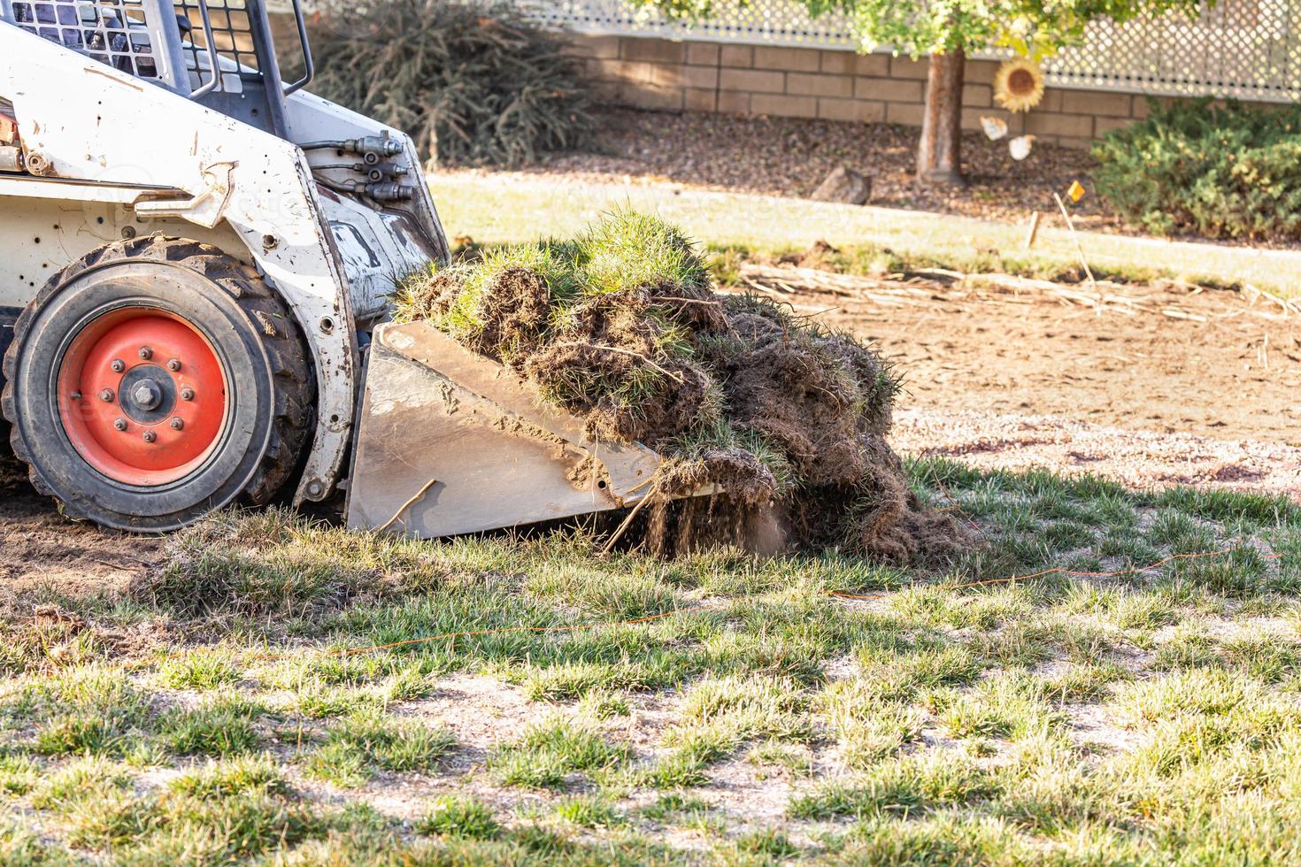 Small Bulldozer Removing Grass From Yard Preparing For Pool Installation photo